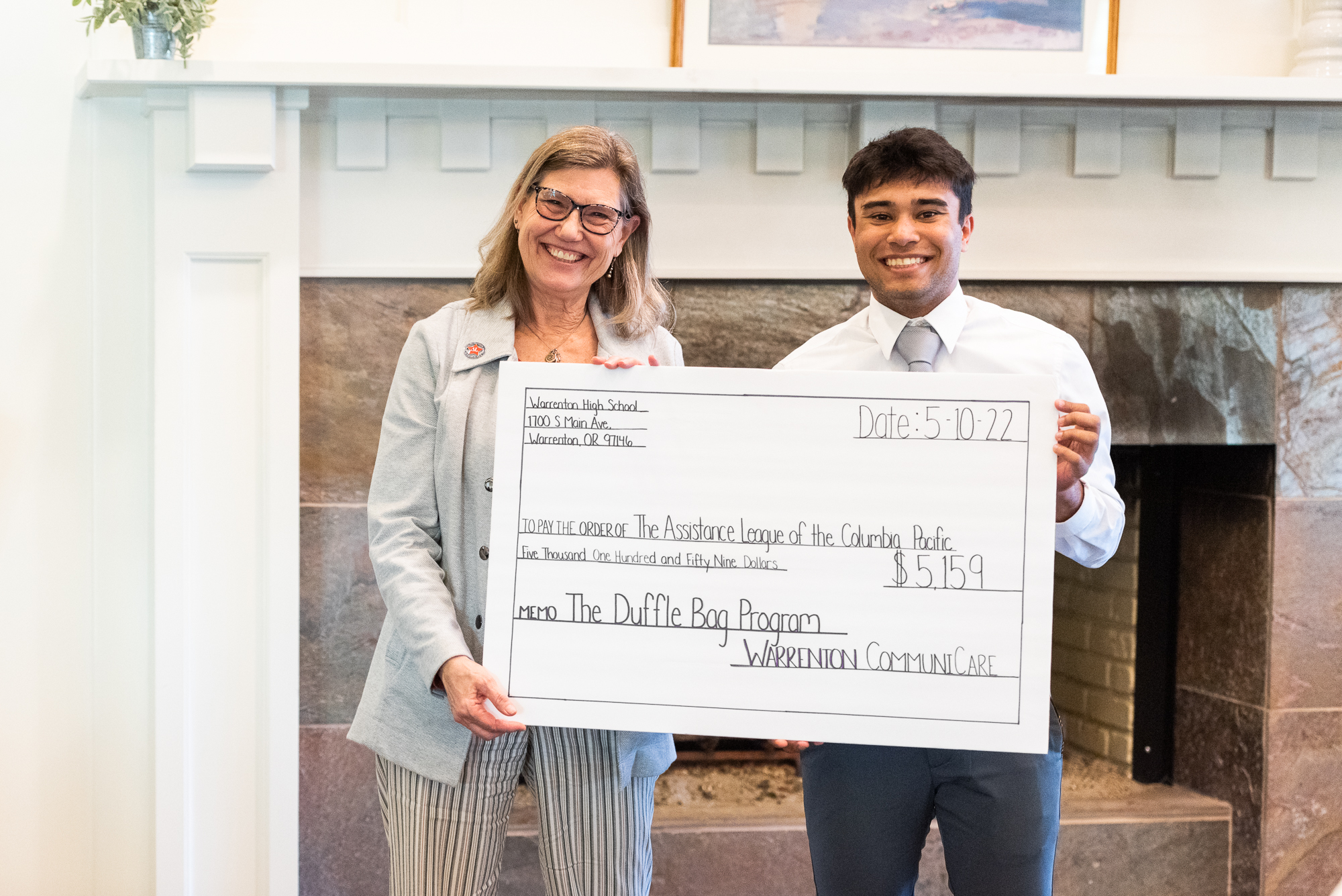 Woman and student standing next to each other holding large novelty check