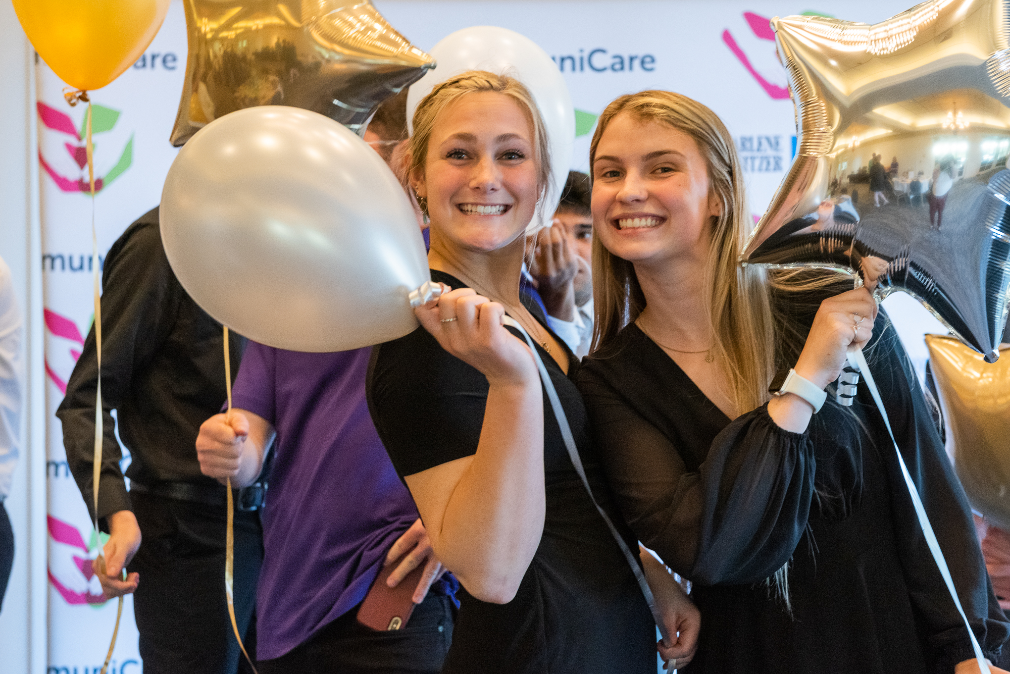 Close up of two students holding balloons and smiling for the camera