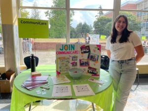 Student standing next to table representing CommuniCare at school club fair.